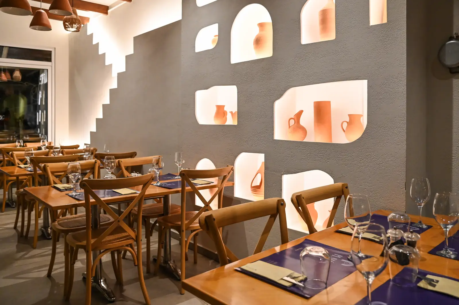 Lit wall niches holding terracotta vessels in the PLATÉA dining room