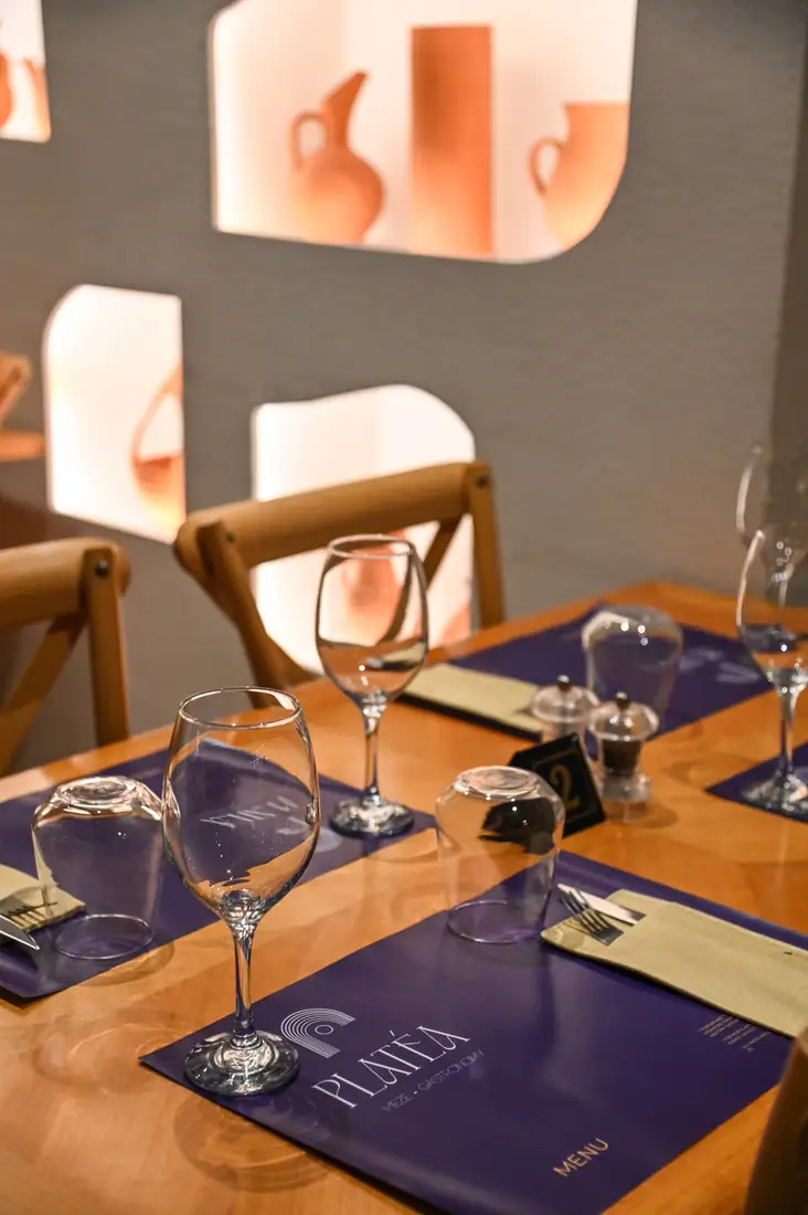 A table set with PLATÉA menus, the lit niches behind